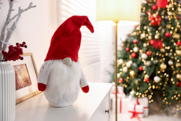 Naklejka premium Funny Christmas gnome on cabinet in decorated room. Space for text