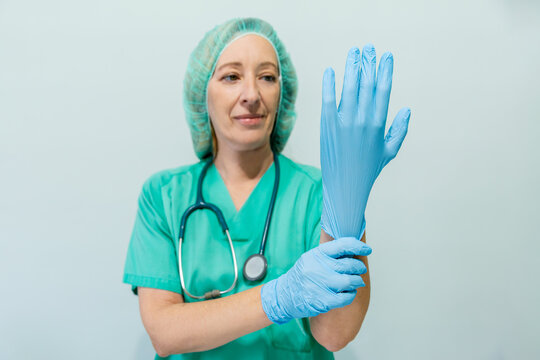 Female nurse preparing with gloves in medical office