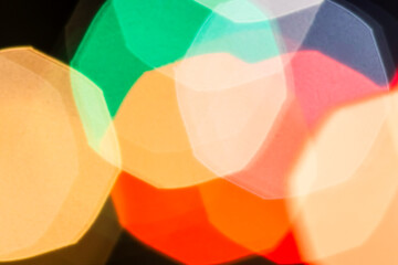Abstract background of colorful, geometric bokeh light effects. Vibrant, unfocused glowing city lights create a festive and modern atmosphere against a dark backdrop