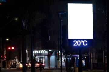 A digital street billboard at night displays the temperature of 20&deg;C. A large blank white screen provides copy space for advertising or public information mockups.