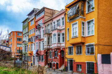 Colorful historic residential buildings with vibrant facades, balconies and vintage details creating a charming street view full of character. Fener, Istanbul, Turkey.