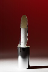 Minimalist applicator with clear gel and droplets standing in metallic holder on red background with copy space for cosmetic serum, skincare innovation and beauty clinic banner
