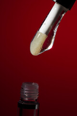 Lip oil applicator with clear glossy formula and bubbles on red background, collection of macro shots for cosmetic branding, skincare hydration and beauty product advertising banners
