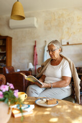 Senior woman relaxing at home reading a book