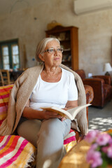 Senior woman relaxing at home reading book