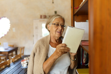 Senior woman reading book finding knowledge on shelf