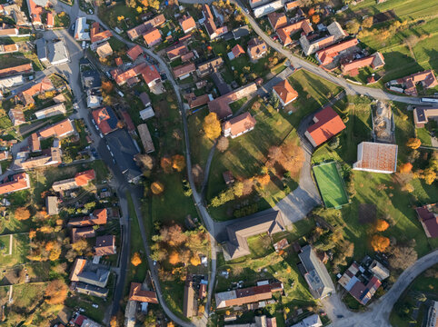 Aerial view of the charming village nestled among vibrant autumn foliage, with red-roofed buildings and winding roads creating a tapestry of color, Hrochot, Banska Bystrica Region, Slovakia.