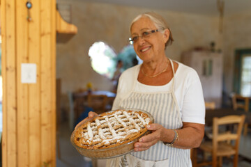 Senior woman smiling holding homemade apple pie