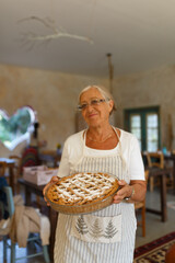 Senior woman presenting homemade apple pie with apron