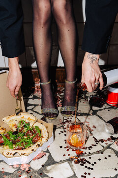 Pouring negroni beside a pizza on a confetti-strewn floor