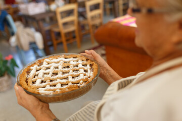 Senior woman holding homemade baked pie with sugar