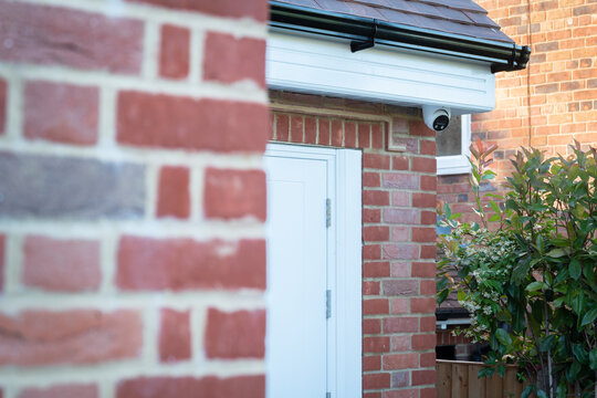 Red brick house exterior with plants and security camera