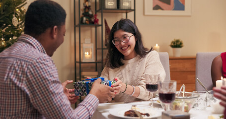 Girl in glasses and red manicure prepared surprise for friend. She gives him Christmas present. Guy in the shirt opened the box, smiled and was happy. They got up and hugged.