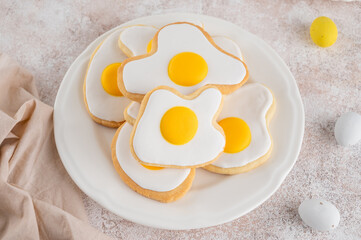 Easter cookies in the form of fried eggs with sugar glaze on a stone background. Funny food idea for kids. Top view, copy space.