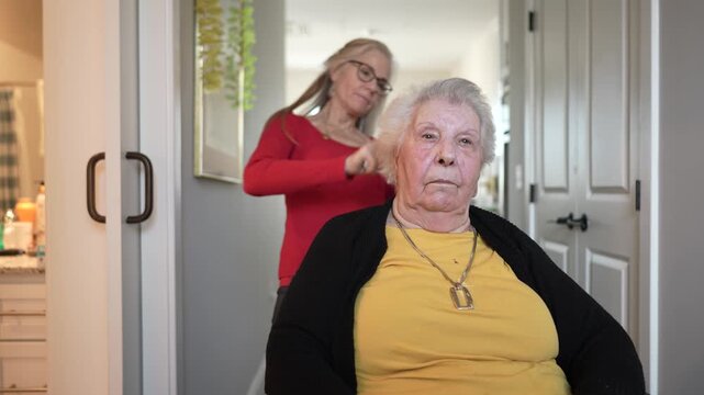 An elderly woman in a home healthcare facility receives gentle care from a caregiver who is focusing on her personal grooming needs.