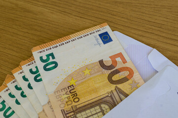 Fifty Euro note partially inside a long white envelope, focusing on the cash-only nature of the transaction