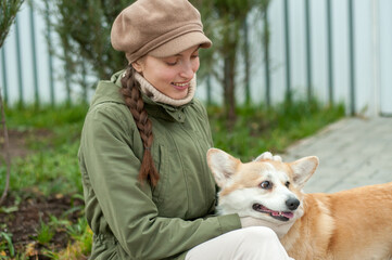 Woman walks with her dog welsh corgi in park. Stylish lady enjoys playtime whith her pet. Autumn season. Fall time.