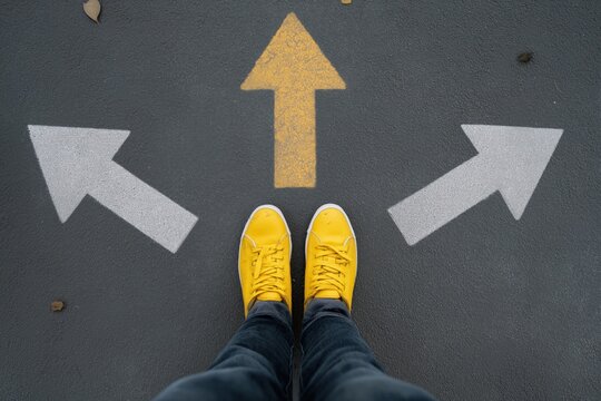 Person deciding path with arrow choices on asphalt in yellow shoes