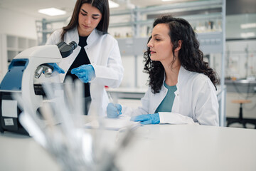 Women scientists collaborating researching with microscope in laboratory