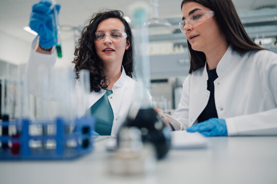 Female scientists analyzing test tube liquid in laboratory - Powered by Adobe