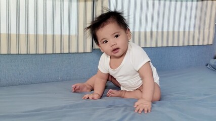 A little baby sitting on a bed, showing balance and posture development