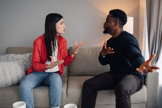 Interracial couple experiencing conflict while arguing on a couch - Powered by Adobe