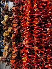 Bundles of dried vegetables such as red chili peppers, dried tomatoes, and dark-colored eggplants. Local market.