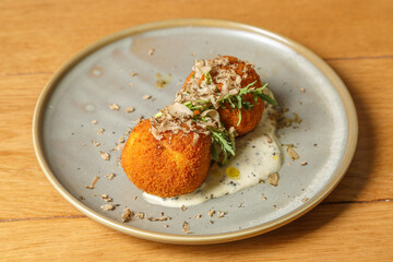 Arancini crémeux sur une assiette grise – entrée italienne sur une table en bois