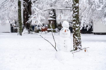 A happy-looking snowman with a carrot nose is sprinkled with falling snow in the open park. Constance, Baden W&uuml;rttemberg, Germany.