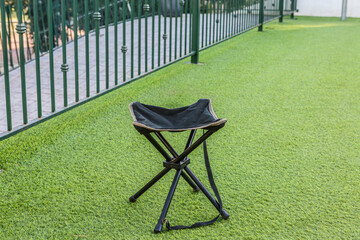 Outdoor folding chair positioned on green artificial grass near a fence