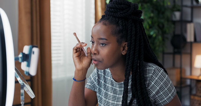 An influencer girl records her everyday eye makeup tutorial at home, using a smartphone on a tripod, sharing opinions about beauty products. - Powered by Adobe