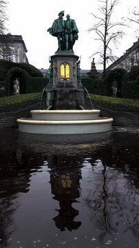 Video of the fountain at Petit Sablon Park in Brussels, Belgium. The clip captures the elegant water flow surrounded by greenery, statues, and historical charm in a peaceful city setting. 