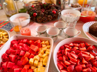 Fresh fruit bowls and holiday breakfast table setup with watermelon, pineapple, papaya and strawberries
