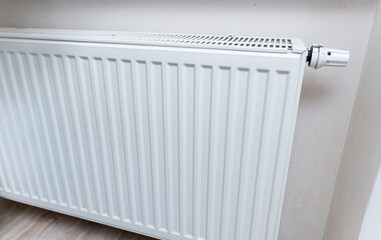 A close-up view of a modern white radiator mounted on a wall, designed for home heating. It adds warmth and comfort to living spaces during cold seasons.