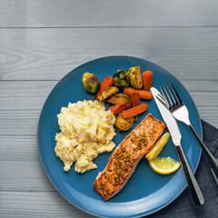 Gourmet Salmon Fillet with Roasted Vegetables on Blue Plate