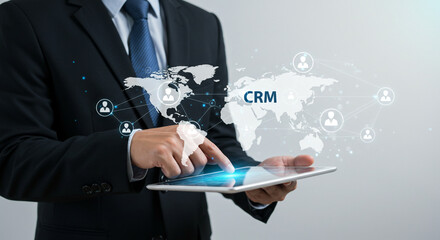 Businessman using CRM on digital tablet with global network connection in modern professional attire with blue tie and suit in soft lighting for corporate marketing