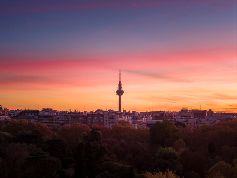 Aerial view of the Pirulí TV tower piercing the horizon amidst a fiery sunset over the city's skyline, Madrid, Community of Madrid, Spain. - Powered by Adobe