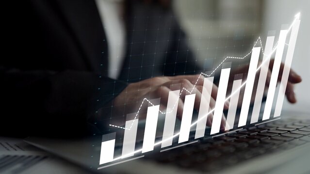 A business professional analyzes growth data on a laptop, showcasing graphs that represent financial performance and market trends in a modern office setup. Copula