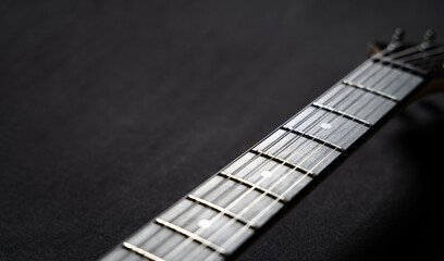 Close-up of an electric guitar neck and headstock on a black background. Musical instrument concept highlighting strings, tuning pegs, craftsmanship, and modern music culture.