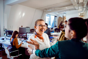 Adult coworkers hugging happily in a creative office