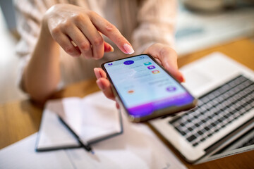 Adult woman focused on mobile banking at home workspace