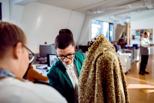Adult woman smiling while fitting coat in fashion studio