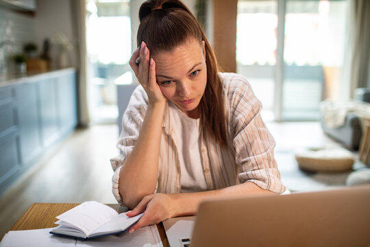 Young adult woman feeling stressed working on laptop at home