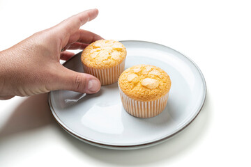 Hand reaching for cupcake on white plate