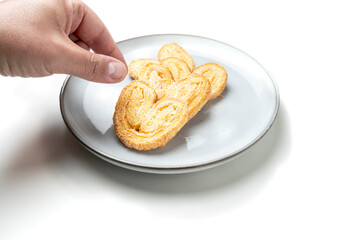 Hand reaching for palmiers on white plate