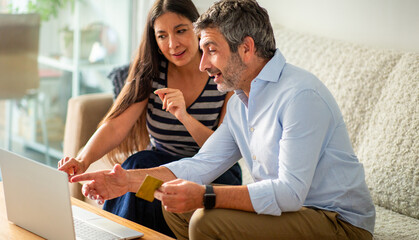 Couple discussing online purchase while using laptop and credit card