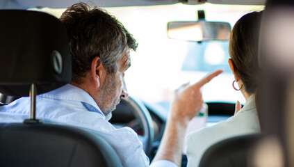 Man pointing and talking about directions with woman while sitting together in a car
