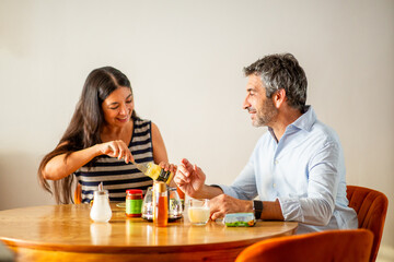 Couple enjoying breakfast together with woman preparing toast and smiling