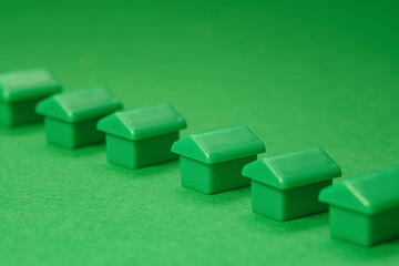 A row of small green house models illustrates real estate growth, housing market trends and property for sale or rent. Perfect for business brochures.