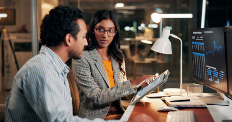 Night, meeting and business people on tablet for finance review, investment and budget planning. Dark, working late and man with woman on tech for financial report, research or stock market in office